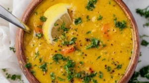 Delicious bowl of lemon lentil soup with fresh herbs and a slice of lemon
