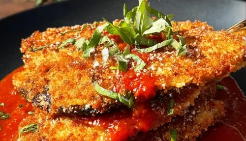 Crispy eggplant schnitzel topped with fresh tomato sauce on a plate