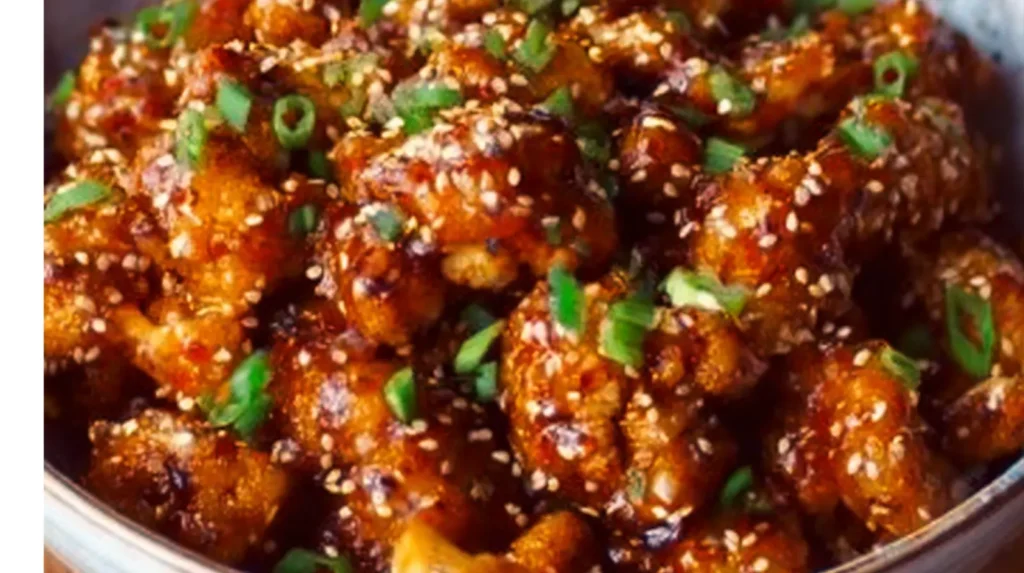 Delicious sticky sesame cauliflower served in a bowl, garnished with green onions.